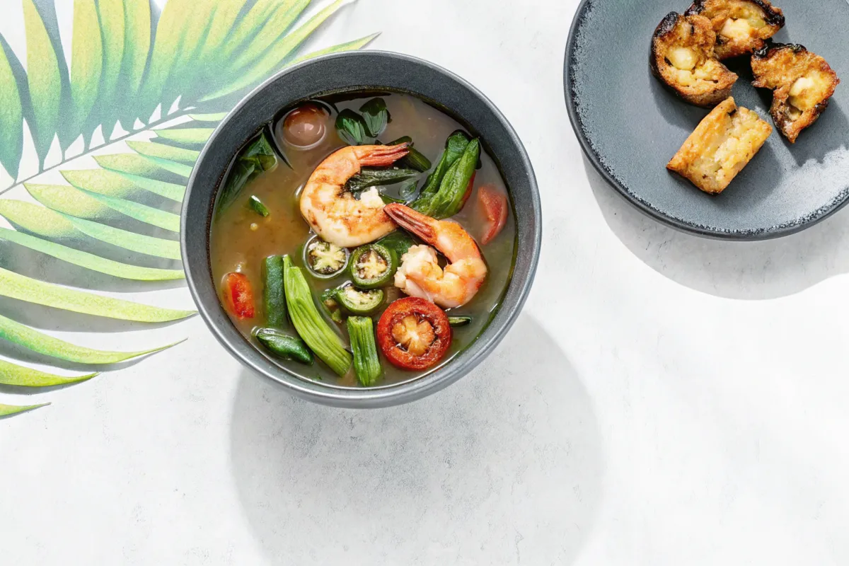 erved Sinigang with pork and vegetables in a clay bowl