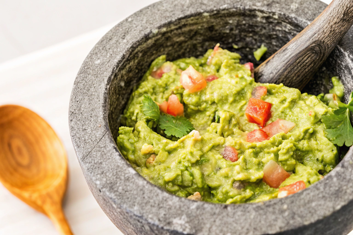 Molcajete guacamole with fresh tomatoes, onions, and cilantro.