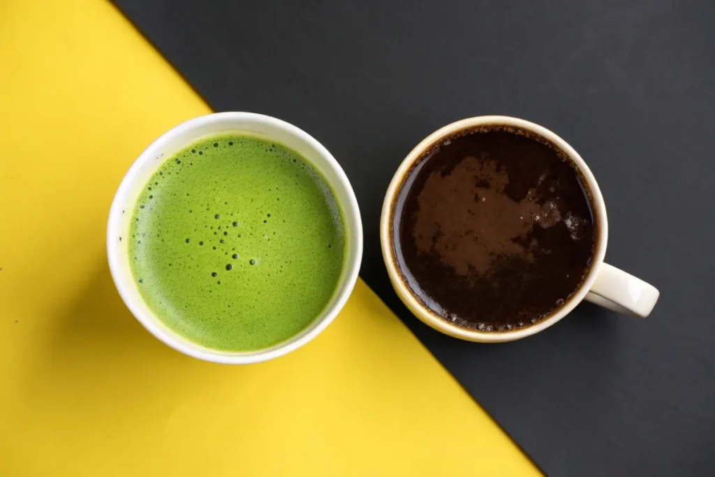 Two mugs filled with matcha and coffee sit on a two-toned background.