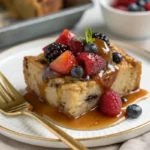 Plated bread pudding with caramel sauce and fresh berries on a white plate